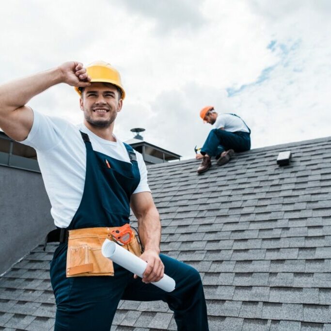selective-focus-of-happy-repairman-holding-rolled-paper-while-coworker-repairing-roof-e1625561369341 selective-focus-of-happy-repairman-holding-rolled-paper-while-coworker-repairing-roof-e1625561369341